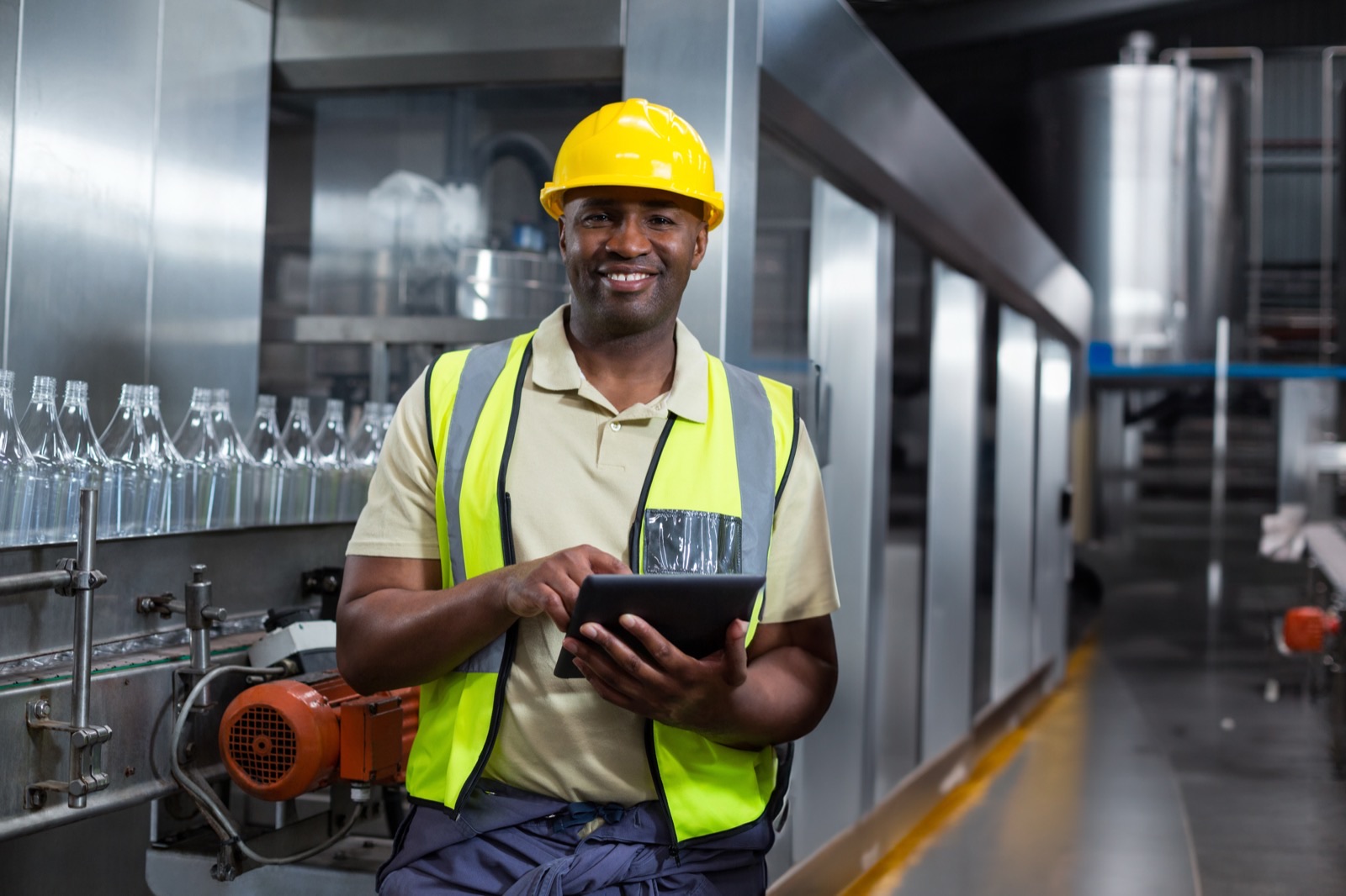 African industrial worker using a tablet beside factory production equipment