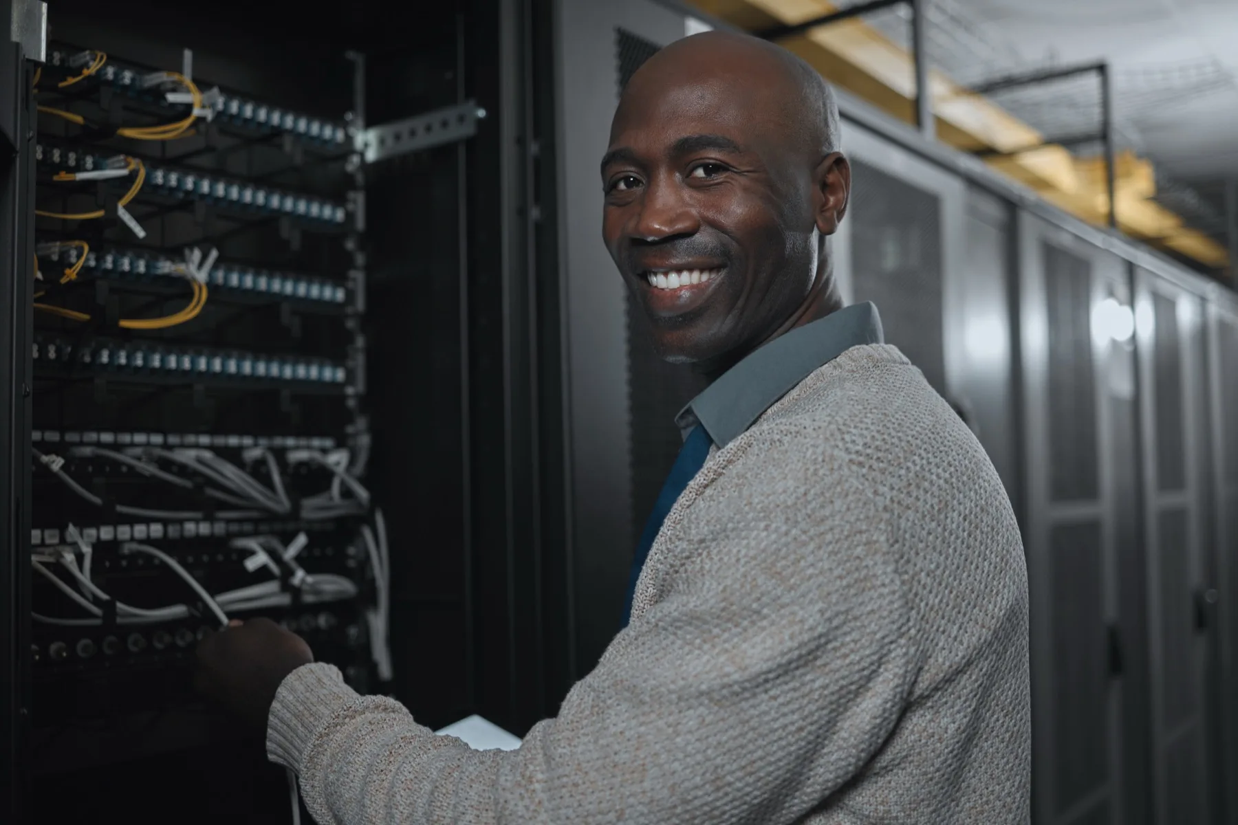 Technician working near structured cabling and network rack equipment